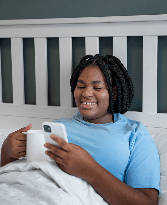 Woman smiling while holding a mug and phone, representing a patient receiving follow-up care